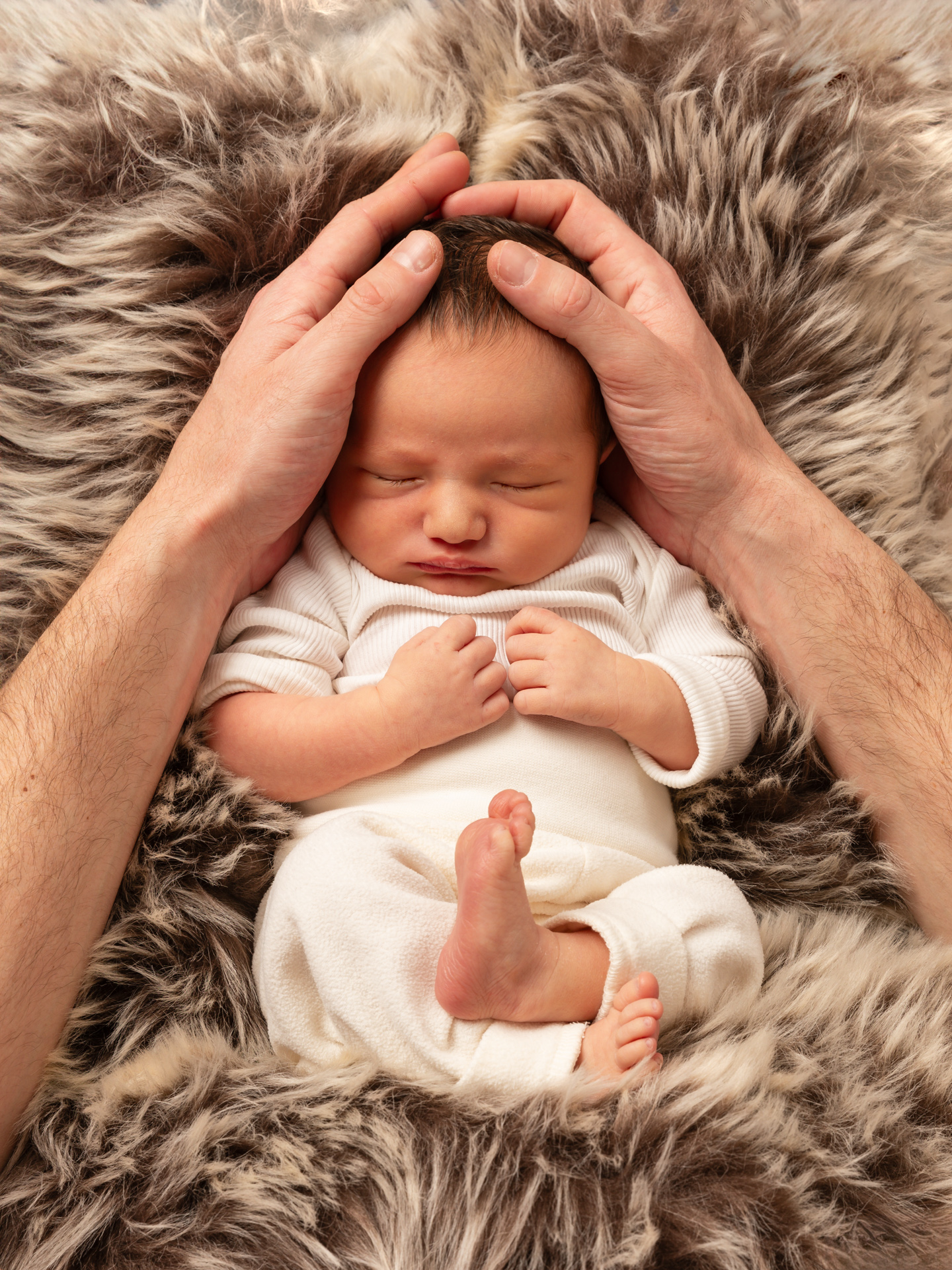 Neugeborenes Baby beschützt in den Händen der Eltern – Emotionale Babyfotos Rheintal