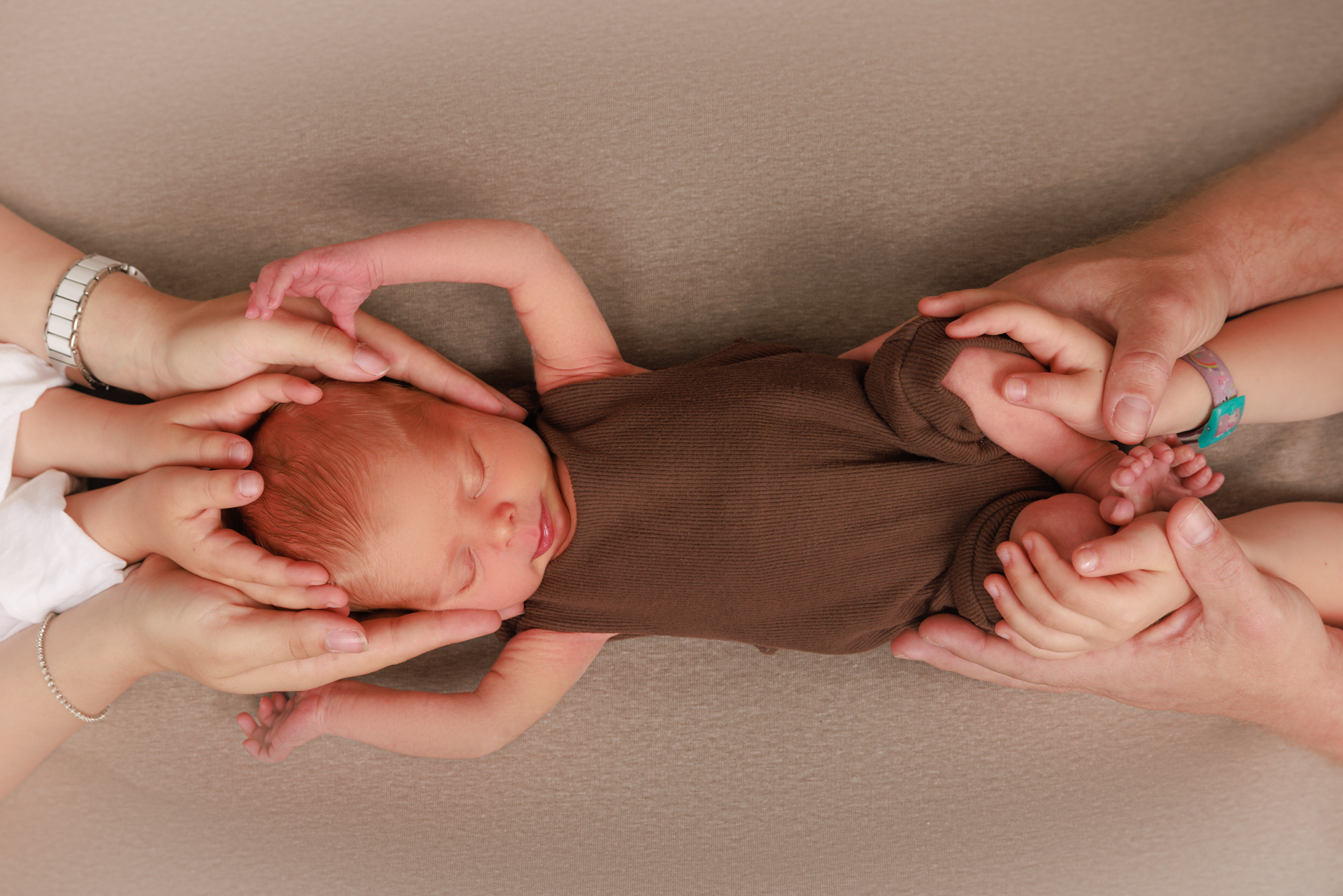 Neugeborenes Baby beschützt in den Händen der Eltern – Emotionale Babyfotos Rheintal