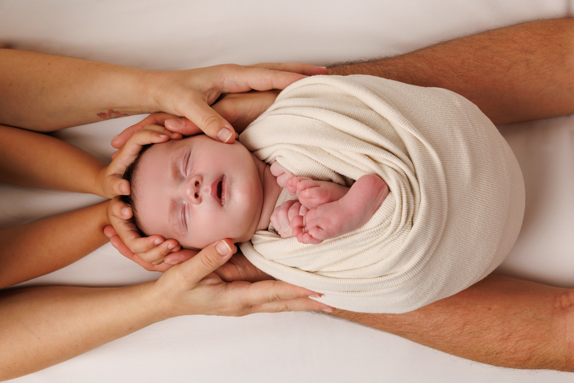 Neugeborenes Baby beschützt in den Händen der Eltern – Emotionale Babyfotos Rheintal